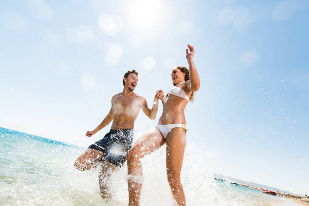 istock Cheerful couple having fun while running through sea in summer day. 1448734179