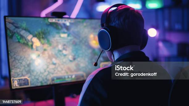 Over The Shoulder Angle Of A Young Female Gamer Winning In A Video Game On Personal Computer In A Neon Lit Living Room At Home Cozy Evening At Home In Loft Apartment Stock Photo - Download Image Now