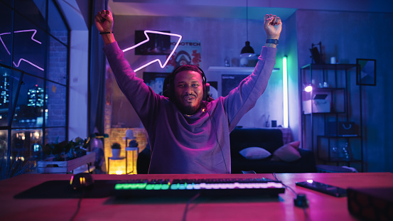 Gaming at Home: African American Gamer Celebrating After Victory in Online Video Game on Computer. Successful Black Man Winning in Online Multiplayer Tournament. POV from Screen Perspective.