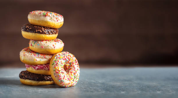 istock Set of different multicolored sweet donuts donuts with icing and sprinkles on brown background with copy space 1448740762