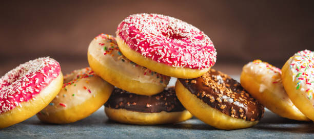 istock Set of different multicolored sweet donuts donuts with icing and sprinkles on brown background 1448741600