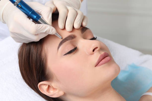 mujer joven durante el procedimiento de maquillaje permanente de cejas en salón de belleza, primer plano - coloreado a mano fotografías e imágenes de stock