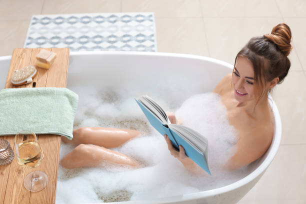 istock Beautiful woman reading book while enjoying bubble bath at home 1448744595