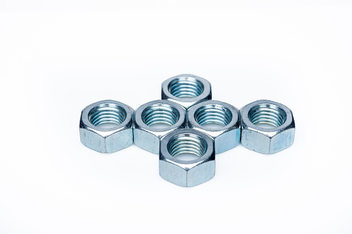 Set of steel nuts. On an isolated white background. With scratches. Close-up studio macro photography.