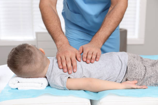 ortopedista masajeando la espalda del niño en la clínica, primer plano. tratamiento de la escoliosis - chiropractic adjustment fotos fotografías e imágenes de stock