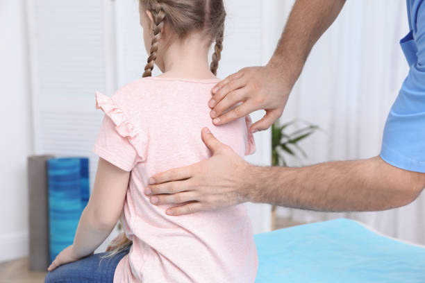ortopedico che esamina la schiena del bambino in clinica, primo piano. trattamento della scoliosi - physical therapy back table patient foto e immagini stock