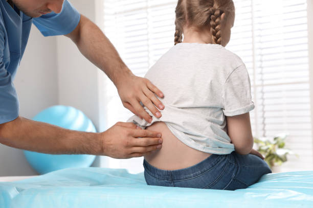 ortopedico che esamina la schiena del bambino in clinica, primo piano. trattamento della scoliosi - scoliosis foto e immagini stock