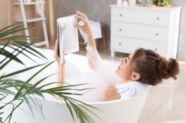 istock Beautiful woman reading book while enjoying bubble bath at home 1448746024