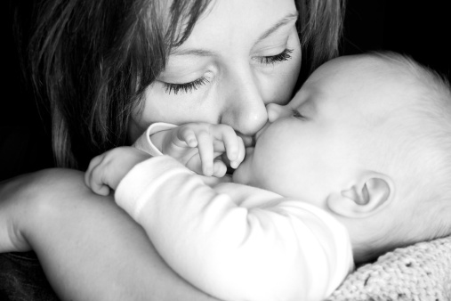 Mother with newborn baby girl holding her close