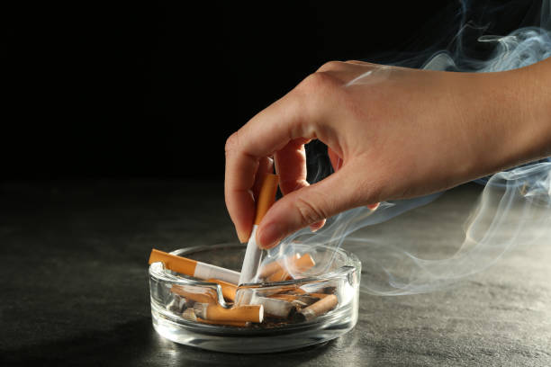 femme éteignant sa cigarette dans un cendrier en verre - mégot de cigarette photos et images de collection