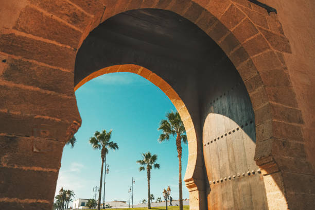 guardando attraverso l'antico cancello del forte palme e cielo a rabat, marocco - ancient arabic style arch architecture foto e immagini stock