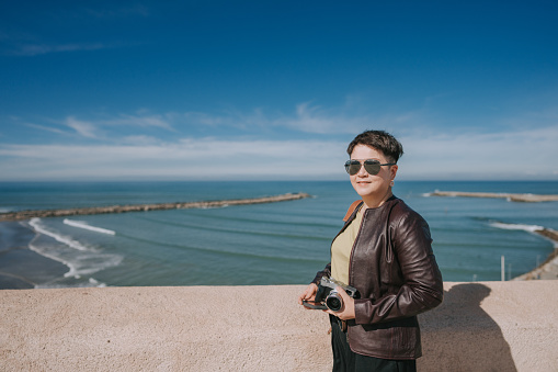 Asian Chinese female tourist standing in front of North Atlantic Ocean beach viewing from Kasbah of the Udayas