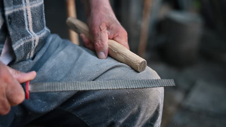 Senior carpenter hands working with a piece of wood an a file