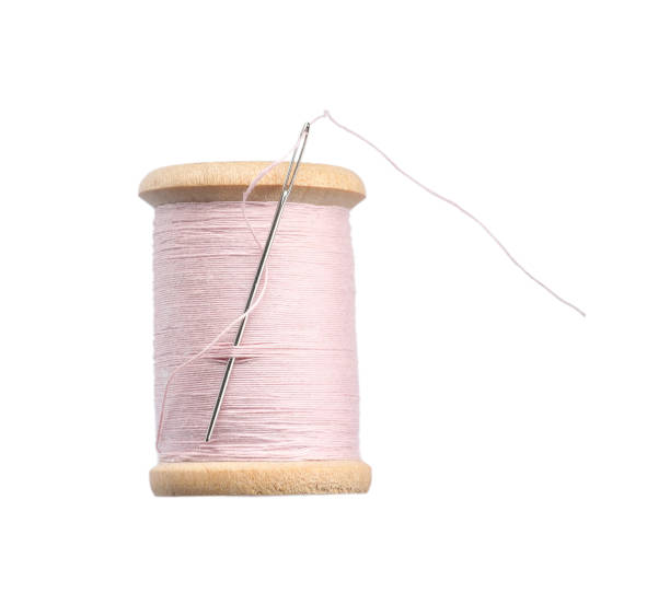 istock Pink sewing thread with needle isolated on white 1448750479