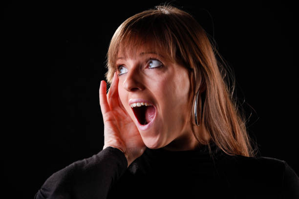 Woman on black background in shock after getting a very good or bad news.