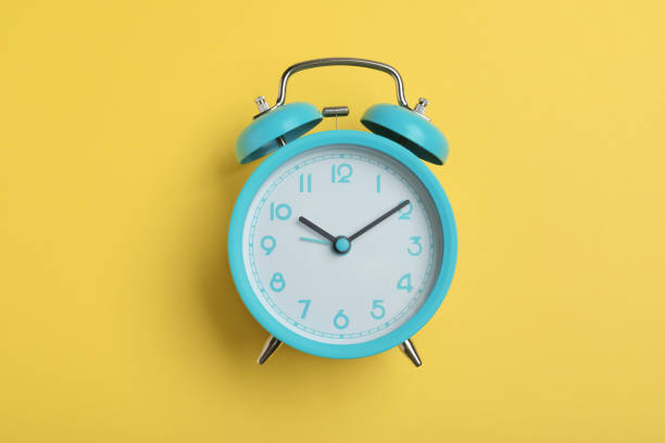 istock Alarm clock on yellow background, top view. School time 1448752836