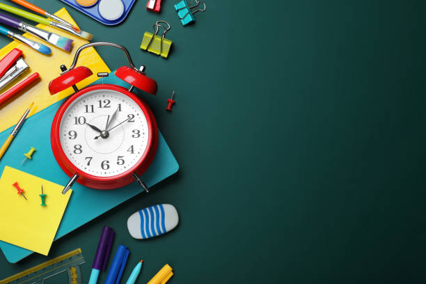 istock Flat lay composition with alarm clock and different stationery on green chalkboard, space for text. School time 1448753708