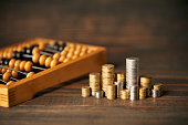 Abacus and stacks of coins over wooden background