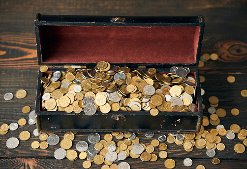 Chest filled with coins of Ukraine on wooden background. Finance, banking and investment concept.
