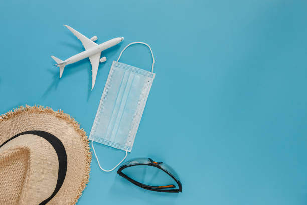 istock Summer holiday blue background with medical mask ,straw hat,  sunglasses. 1448754849