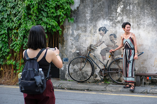 George Town, Malaysia - November 2022: Tourists taking pictures with a graffiti in George Town on November 16, 2022 in Penang, Malaysia.