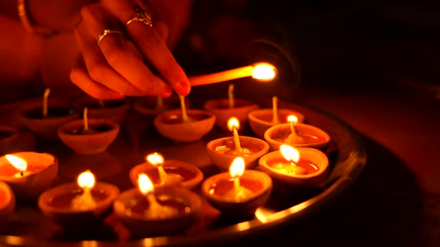 A female hand holding oil lamps plate in hand during deepavali festival. Diya or traditional clay lamps