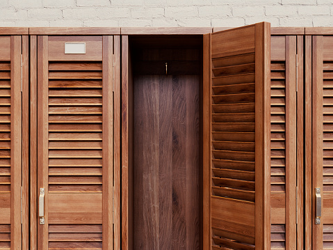 A row of vintage wooden louvered door lockers with one open door revealing an empty interior - 3D render