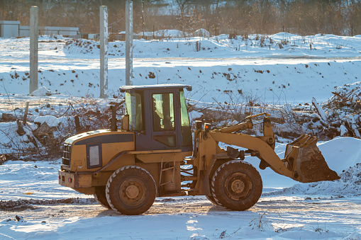 Yellow front loader wheeled tractor at a construction site at winter