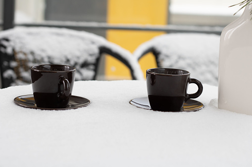 photo on a table covered with snow there are cups of coffee on saucers