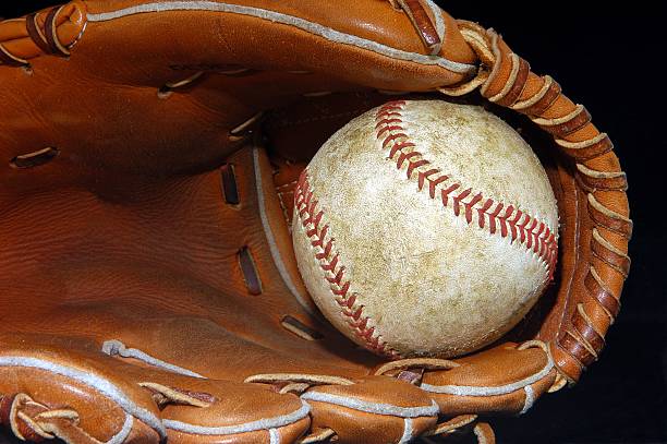 Beat up, used baseball in a well worn fielders glove