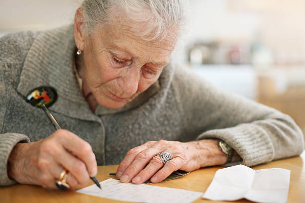 istock Senior woman writing on a paper 144877018
