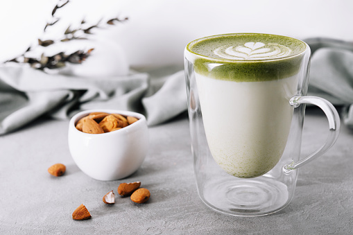 glass of green tea matcha latte with almonds