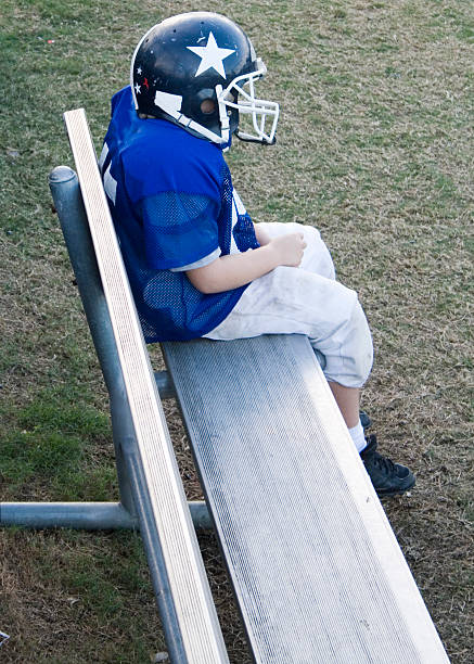 Lone benched youth football player. stock photo