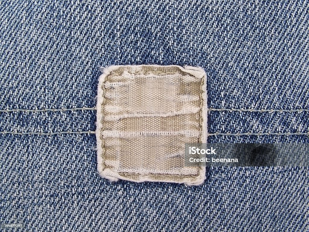 Faded Denim Pocket Close up of a faded blue jeans pocket with a blank, frayed tan denim tag. Backgrounds Stock Photo