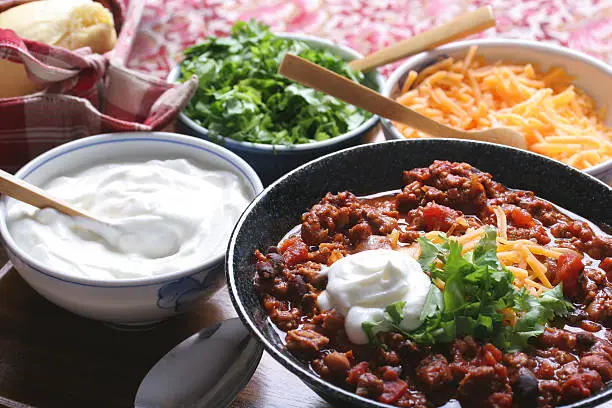 Chili with cheese, sour cream, cilantro and homemade roll