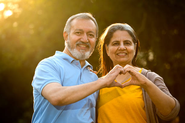 istock Romantic senior couple showing heart in park 1448773539