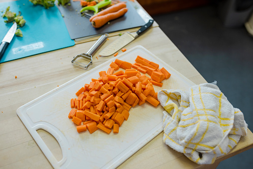 A close-up shot of chopped up carrots on a cutting board in the kitchen at a warm hub/food bank which is a safe place for people to enjoy a warm and friendly environment in the community with the current cost of living increasing.