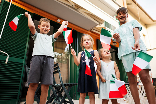 Happy four kids with italian flags celebrating Republic Day of Italy.