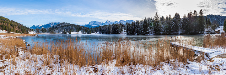 calm panoramic winter landscape with lake, snow and mountain range