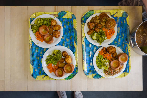 A directly above shot of two trays with of roast dinners on plates, ready to be served to people visiting a warm hub/food bank which is a safe place for people to enjoy a warm and friendly environment in the community with the current cost of living increasing.