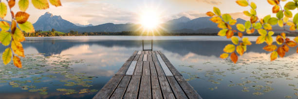 panoramic view over lake with jetty in sunset stock photo