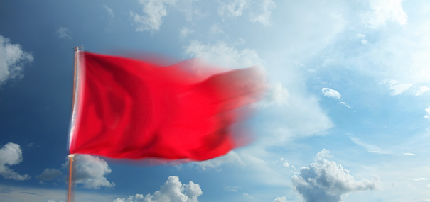 Red blank waving flag over sky