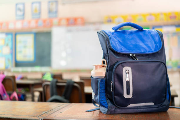 Front of stylish school bag backpack supplies on a table desk at the green chalkboard, Back to school education concept. stock photo