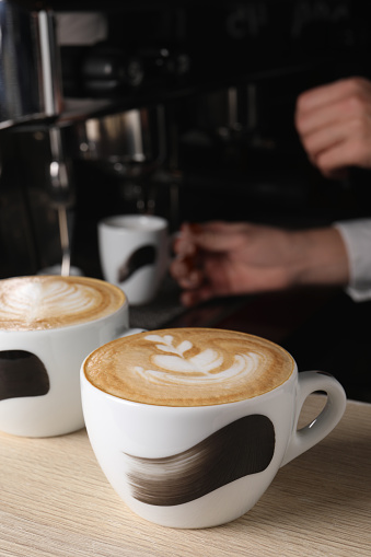 Barista working in cafe, focus on counter with cups of fresh aromatic coffee