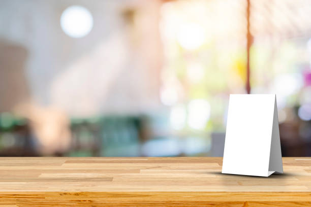 istock Stand Mock up Menu frame tent card blurred background design key visual layout. Empty wood table top with cafe restaurant interior blur background 1448780463