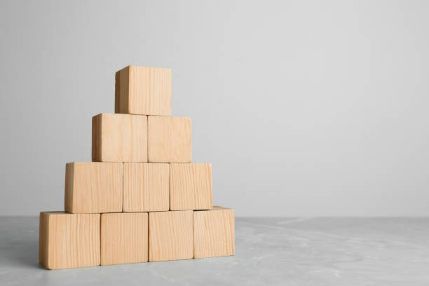 istock Pyramid of blank wooden cubes on grey table against light background. Space for text 1448782007