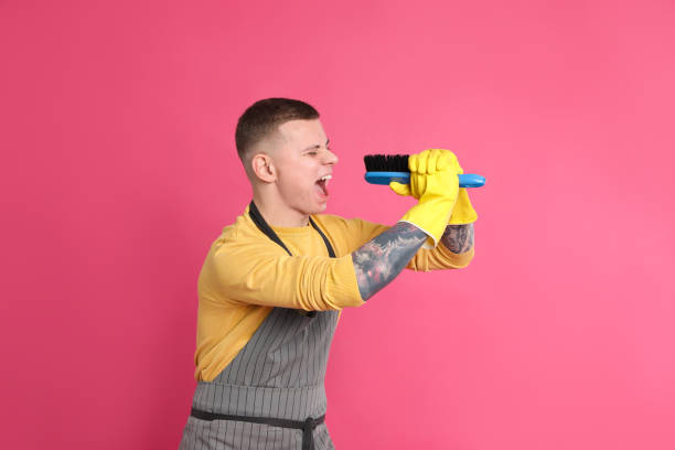 istock Handsome young man with brush singing on pink background 1448783343