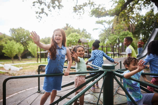 istock Laughing children waving while riding on a merry-go-round in summer 1448783580