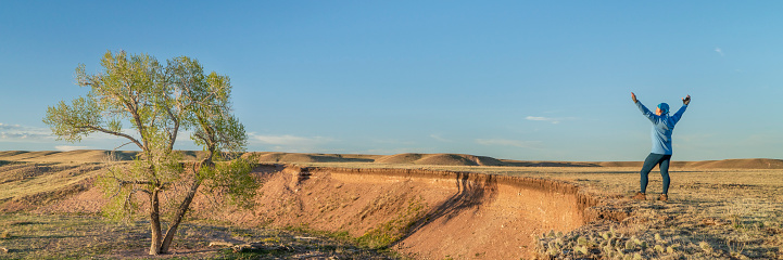 prairie in northern Colorado at early spring sunset with a lonely male figure on a cliff - Soapstone Prairie Natural Area near Fort Collins, panoramic web banner