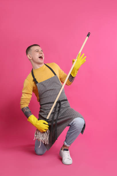 istock Handsome young man with mop singing on pink background 1448784519